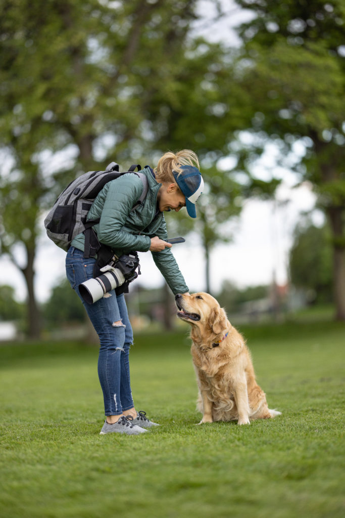 woman with a cap petting a golden retriever dog
