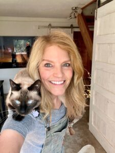 blond woman with a siamese cat on her shoulders